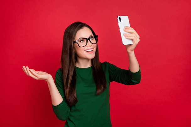 Photo of attractive girl hairdo raise hand take selfie smart phone wear trendy green outfit eyewear isolated on shine red color background. - Photo, image