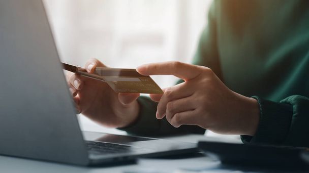 Woman holding a credit card, she uses a credit card to pay for goods and services online, the concept of using a credit card for online shopping, ordering goods and services on the website. - Foto, Bild
