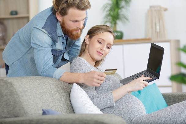 couple enjoying online shopping sitting on sofa at home - Fotó, kép