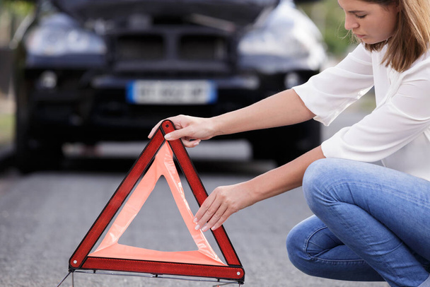 woman putting a safety red triangle - Фото, зображення