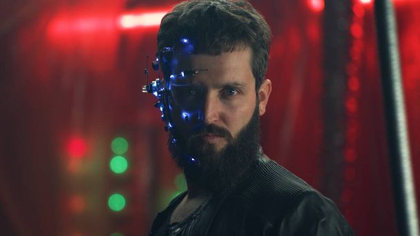 A fiatal fickó LED-es fejhallgatót visel, a fekete akasztórudak mögött áll, és a kamerába néz. Cyberpunk és futurisztikus koncepció. Neonfények a háttérben. - Fotó, kép