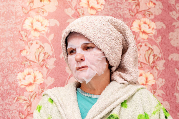 Пожилая женщина в косметической маске на лице. Уход за кожей - Фото, изображение