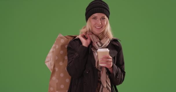 Atraktivní žena se usmívá na kameru s nákupními taškami na zelené obrazovce. Na zelené obrazovce, která má být zadána nebo složena. - Záběry, video