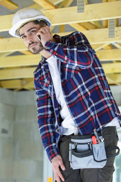 builder on the phone by a ladder - 写真・画像