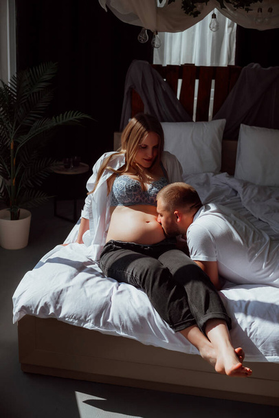feliz pareja casada en un fondo blanco en el estudio; una chica embarazada y su marido - Foto, imagen
