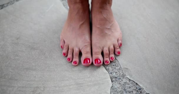 Pies femeninos con uñas rojas descalzas sobre losas de pavimentación. Hermosos pies femeninos - Metraje, vídeo