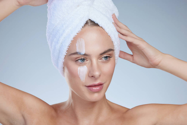 Haar ochtendschoonheidsact. Studio shot van een aantrekkelijke jonge vrouw poseren met een handdoek op haar hoofd tegen een grijze achtergrond - Foto, afbeelding