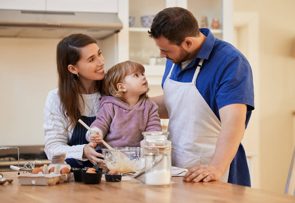 Siempre serás nuestro bebé. una familia horneando juntos mientras una niña revuelve un tazón de masa de pastel - Foto, Imagen