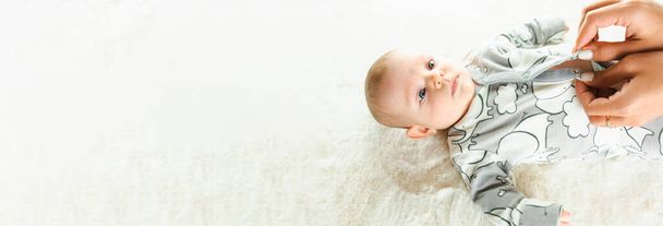 Baby cute child banner. Happy cute baby kid girl lying on white bed background. Light background. Little child. Serious emotion - Foto, Imagen