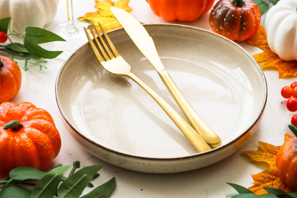 Őszi asztalterítés. Üdülési vacsora. Kézműves lemez, arany evőeszközök, üveg, gyertya és őszi dekorációk. - Fotó, kép