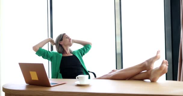 Glückliche, friedliche Arbeiterfrau lehnt sich auf bequemen Bürostuhl und hält die Hände hinter dem Kopf entspannt während der Pause im Arbeitstag. Ruhe und Entspannung nach getaner Arbeit und Wegschauen beim Träumen vom Urlaub - Filmmaterial, Video