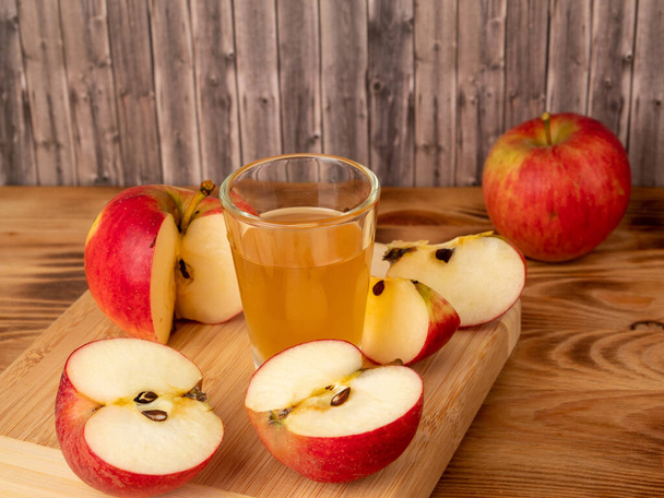 木製の背景にリンゴとガラスのアップルサイダー酢。アップルサイダー酢とリンゴ. - 写真・画像