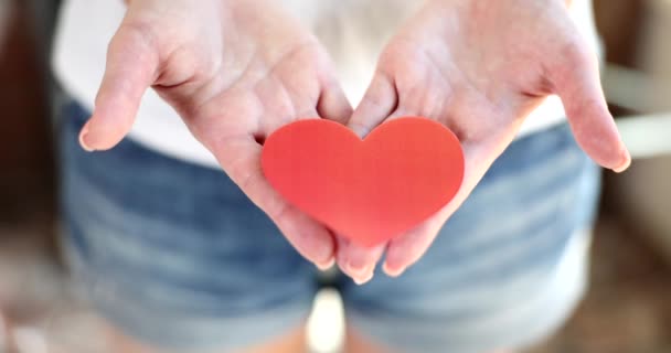 Руки женщины держат красное сердце, сделанное из бумаги. Валентина или волонтерская помощь - Кадры, видео