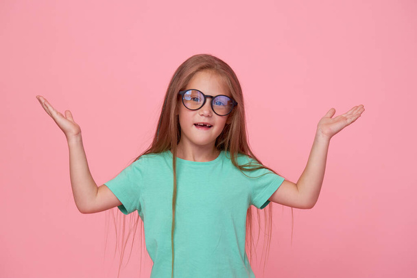 Portrait of cute toddler girl child bespectacled over pink background. Advertising childrens products. Funny face - Foto, Bild