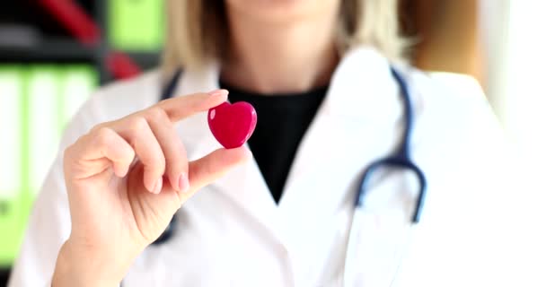 Orvos kardiológus sztetoszkóppal és vörös szívvel a klinikán. Kardiológiai szolgáltatások és egészségbiztosítás - Felvétel, videó