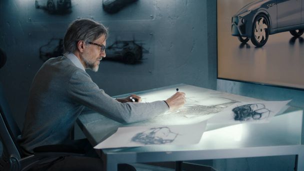 An automotive engineer and designer transfers sketches of prototype car and makes design corrections with a digital display graphics touch sreen table using stylus pen. - Фото, зображення