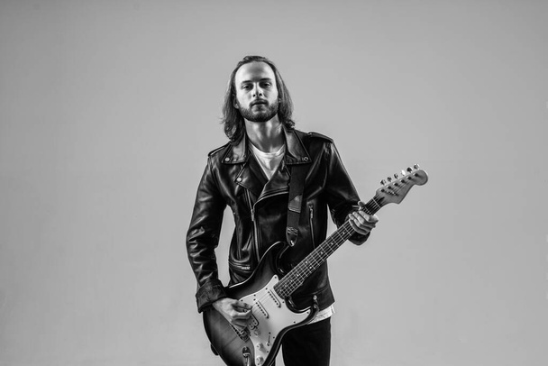 rock star. masterfully playing rock music. stylish crazy man. string musical instrument. bearded rocker in leather jacket. man long hair play electric guitar. music style. musician guitar player. - Zdjęcie, obraz