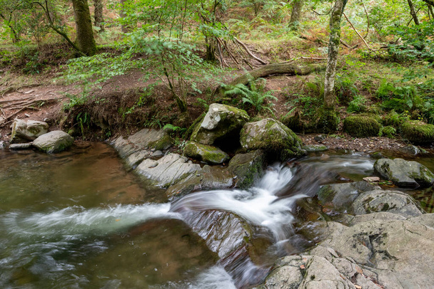 Longue exposition d'une cascade sur la rivière Horner Water qui coule à travers les bois Horner dans le Somerset - Photo, image