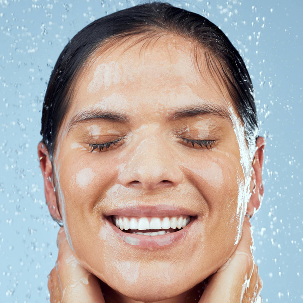 Лучше свежий. Студийный снимок привлекательной молодой женщины, принимающей душ на синем фоне - Фото, изображение