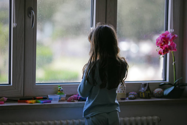 Mladá dívka 6-7 let dívá z okna. - Fotografie, Obrázek