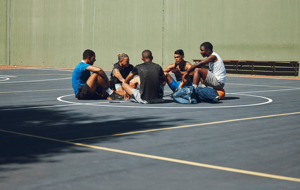Teamwork, basketball and planning with friends relax on sports court for training, workout and fitness together. Exercise, goals and health with athlete men relax after game competition in outdoor. - Photo, Image
