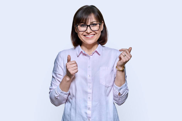 Happy emotional middle aged woman looking at camera on light studio background. Attractive smiling mature female with glasses, gesticulating with her hands. Work job business, 40s people concept - Foto, Imagen