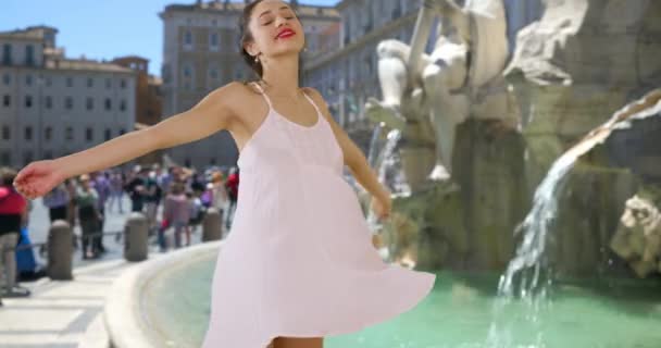 ローマの噴水によって渦巻く屈託のないラティーナの女性のスローモーション。美しい幸せな観光客の白い太陽の下で楽しく笑みを浮かべて回る。4k - 映像、動画