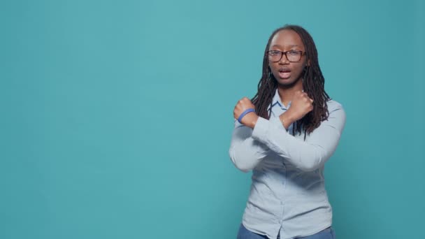 Frau macht Stop-Abstoßungsgeste mit den Armen, steht über blauem Hintergrund im Studio. Verweigerung und verbotenes Symbol mit verschränkten Händen zeigen, negative Emotionen und Abneigung ausdrücken. - Filmmaterial, Video