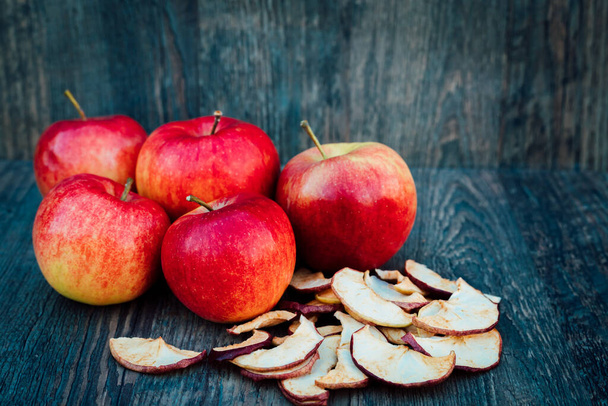 Jablka, sušená jablka a růžové boky leží na tmavém dřevěném stole Podzim. Kvalitní fotografie - Fotografie, Obrázek