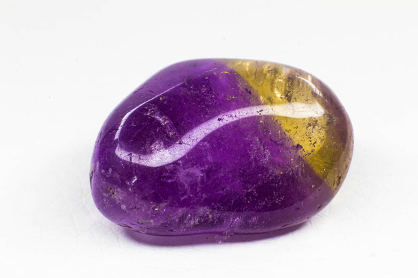 Macro de piedra cristalina amarilla y púrpura tumbada real aislado en una superficie blanca. Cristal morado con un poco de coloración amarilla en el borde. Una combinación cristalina de amatista púrpura y citrino amarillo - Foto, imagen