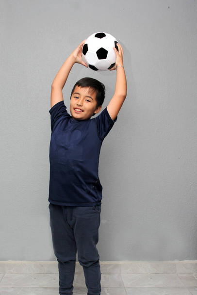 Hispânico Latino menino de 8 anos joga com uma bola de futebol muito animado que ele vai ver a Copa do Mundo e quer ver sua equipe ganhar - Foto, Imagem