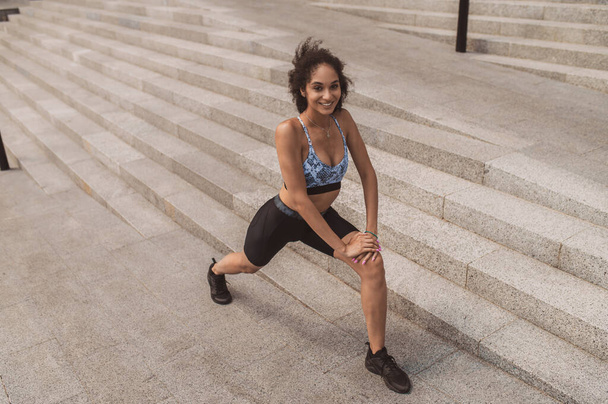 La pierna se abalanza. Una chica en ropa deportiva haciendo saltos de pierna durante el entrenamiento al aire libre - Foto, imagen