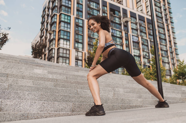 Fitness. Chica joven delgada en pantalones cortos apretados haciendo ejercicio al aire libre - Foto, imagen
