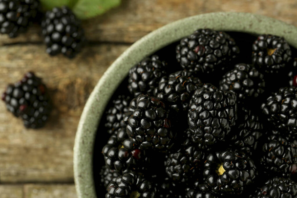 Bowl with fresh ripe blackberries on wooden table, top view - Photo, image