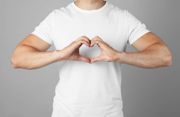 Man making heart with hands on grey background, closeup - Foto, imagen