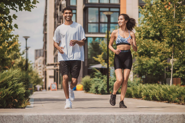 Gemeinsam Sport treiben. Zwei junge Leute in Sportkleidung laufen zusammen - Foto, Bild