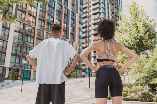 Young people. Two young people in sportswear standing on the mutistorey building background - 写真・画像
