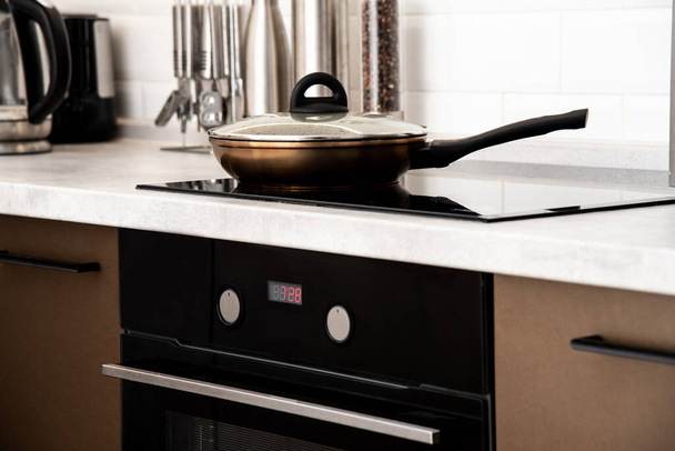 Обсмажування сковороди на сучасній кухні з індукційною плитою
 - Фото, зображення