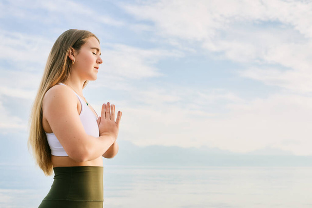 Piękna duchowa kobieta medytująca nad jeziorem, namaste gest - Zdjęcie, obraz