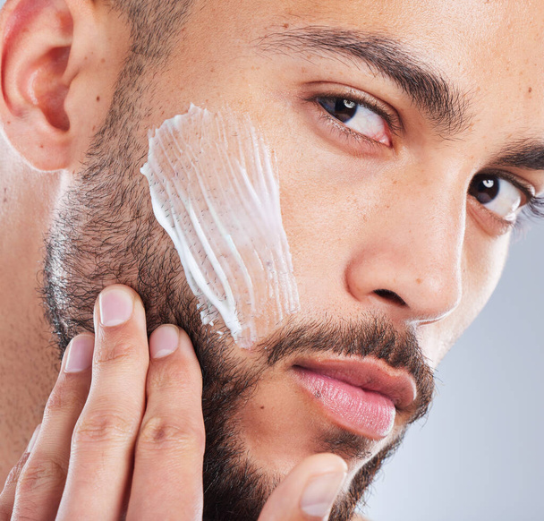 Moisturise like you mean it. Studio shot of a handsome young man applying a skincare product to his face against a grey background - Photo, image