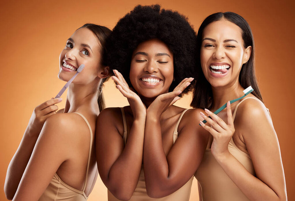 Beauty, smile and dental with women and toothbrush for teeth, oral healthcare and hygiene. Orthodontics, lifestyle and diversity with girls against orange background for wellness, clean or dentistry. - Photo, image