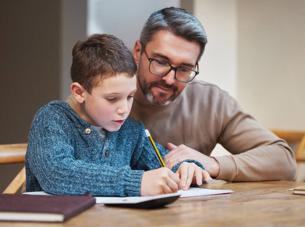 Neem de tijd en je krijgt het. een vader die zijn zoon helpt zijn huiswerk af te maken - Foto, afbeelding