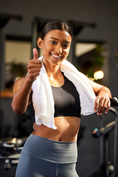 Я одобряю это фитнес сообщение. Портрет здоровой молодой женщины, показывающей большие пальцы во время тренировки в спортзале - Фото, изображение