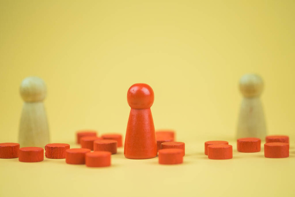 Красная деревянная фигурка, стоящая перед группой. Концепция лидерства и управления. - Фото, изображение