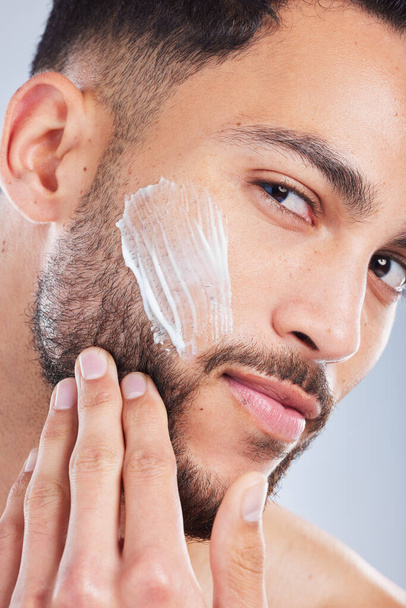 Ill be looking like a million bucks in a bit. Studio shot of a handsome young man applying a skincare product to his face against a grey background - Photo, Image