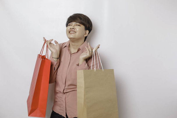 A happy young woman is wearing pink shirt and holding presents or shopping bag. - Foto, imagen