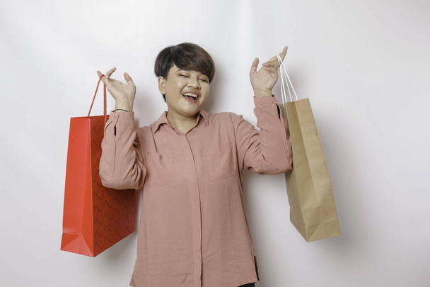 A happy young woman is wearing pink shirt and holding presents or shopping bag. - Φωτογραφία, εικόνα