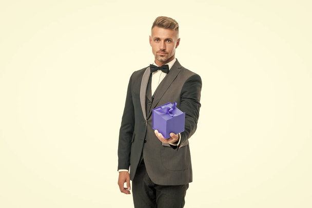 man in tuxedo and bow tie hold present box isolated on white background. - Foto, Imagen
