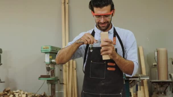 家具工場で働く白人プロの男性ハンサムな大工の木製のベニヤキャリパーを使用して素晴らしいスランプを測定する. - 映像、動画