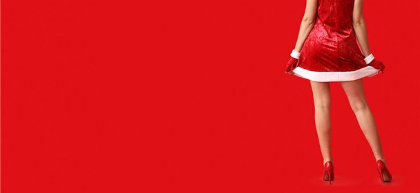 Sexy young woman in Santa costume on red background with space for text - Foto, imagen